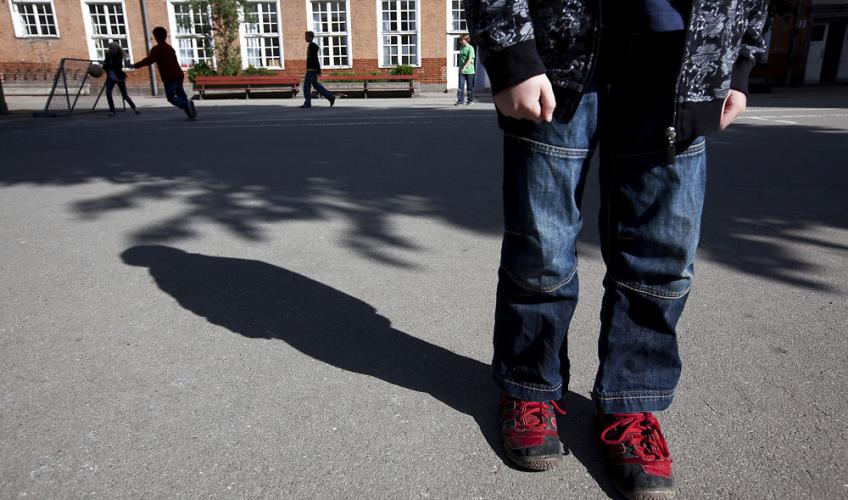 person i skolegård fotografereret så kun benene er synlige